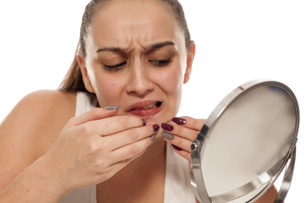 一位年轻女子在镜子上捏着自己的青春痘图片下载