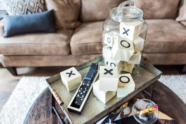 游戏室托盘架与x和o，多米诺骨牌，在舞台模型房子或公寓的咖啡桌上棕色皮革沙发图片下载