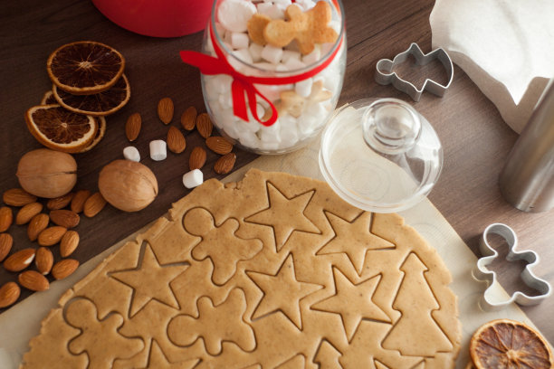 圣诞烘培背景快乐。从以上。生面团放在木板上，用擀面杖和饼干模具做成圣诞节的形状。圣诞饼干的准备图片下载