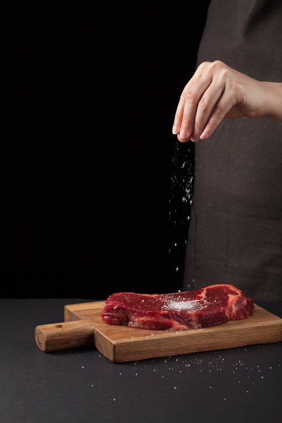 牛排和盐的厨师在背景与自由空间的文字设计或标识菜单餐厅。垂直的照片。食品的背景。黑色文本区域。本空间图片下载