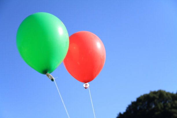 蓝色的天空下，红色和绿色的气球图片下载