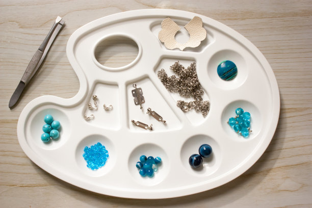 在白色调色板上制作浅蓝色珠宝的珠子和组件。图片下载