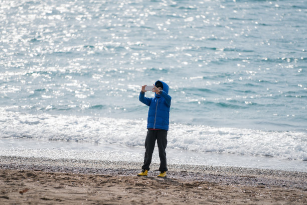 在海滩上用手机自拍的快乐男孩图片下载
