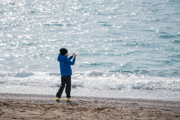 在海滩上用手机自拍的快乐男孩图片下载