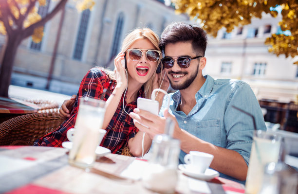 约会。年轻夫妇在咖啡馆喝咖啡和玩手机。爱情、约会、科技、生活方式图片下载