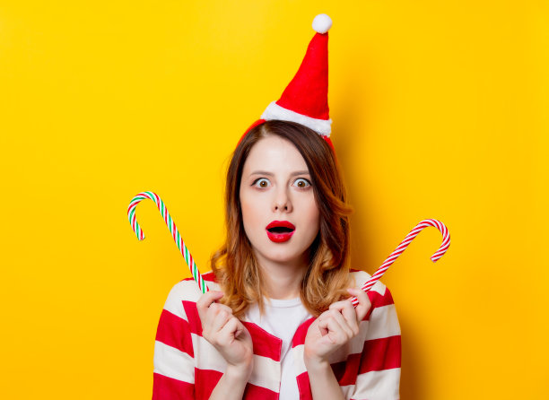 戴着圣诞老人帽和拐杖糖果的女人图片下载