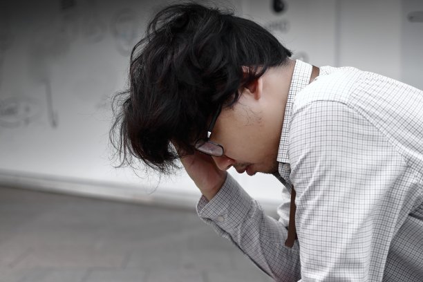 压力沮丧的年轻亚洲商人用手捂着脸。图片下载