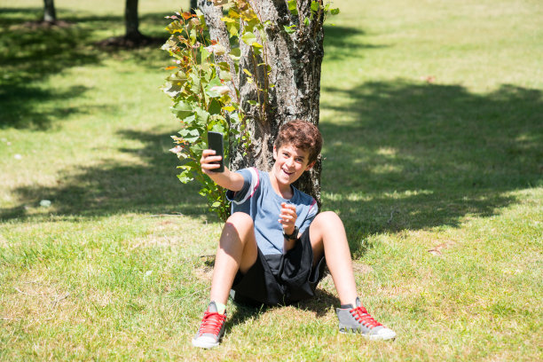 男孩用移动在花园里图片下载