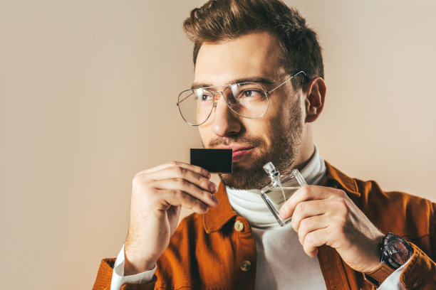 一幅沉思的男子的肖像，手拿香水，孤立地看着远处的米色图片下载