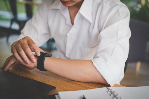 商人在工作场所看智能手表。启动人员查看手表时间。在办公室工作的年轻男性企业家。图片下载