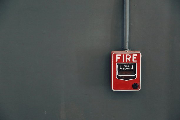 深灰色的墙上有一个红色的火警拉站。图片下载