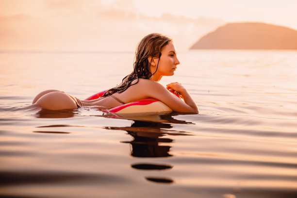 日落时在海里游泳的完美女人。苗条的女人在海边度假放松图片下载