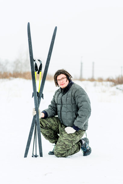一个留着长发绺的年轻人带着滑雪装备坐在雪地上图片下载