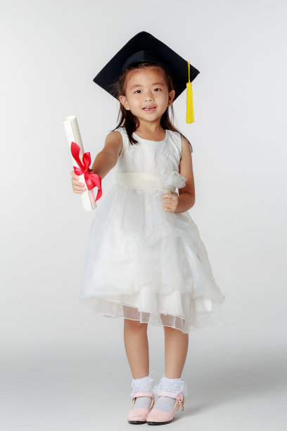 可爱的亚洲小女孩穿着幼儿园毕业服，戴着学位帽和学位服，在白色背景下摆姿势，教育理念图片下载
