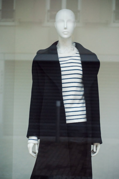 在时装店的女装陈列室里，模特穿着海军蓝条纹套头衫和冬季大衣图片下载