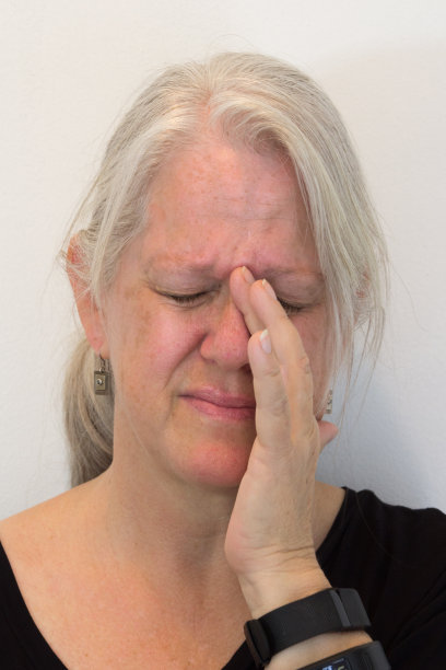 成熟的女人，自然不化妆，鼻窦压力，疼痛，手对脸，中性背景图片下载