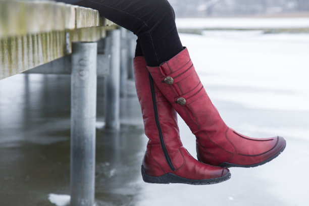 冬日里，一个女人坐在结冰的湖面上的人行桥上。冬天穿的靴子。在大自然中积极的生活方式。冬天的概念。图片下载