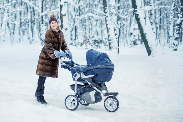 女人在冬天跳舞，推着婴儿车。图片下载