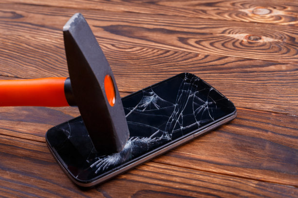Hammer hits the smartphone on the broken screen. 在木制的背景上。特写镜头。图片下载