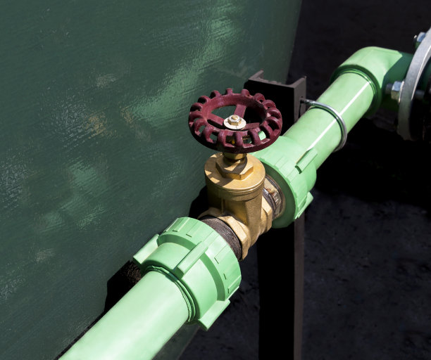 手柄红色的金属闸阀在钢制管道上用连接件用螺钉和螺母连接。图片下载