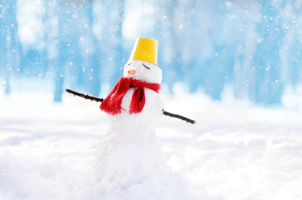 戴围巾、水桶帽和胡萝卜鼻子的手工雪人在雪地公园素材图片