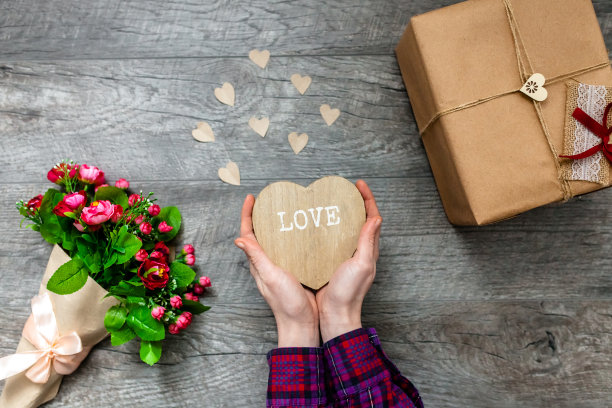 女人手里拿着一颗木制的心，情人节，浪漫的照片。带礼物和一束鲜花，带爱心和礼物，适合做广告图片下载