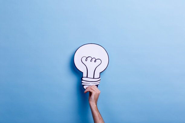 在蓝色背景上，一个男人的手拿着一个灯泡的图片。理念的概念。图片下载