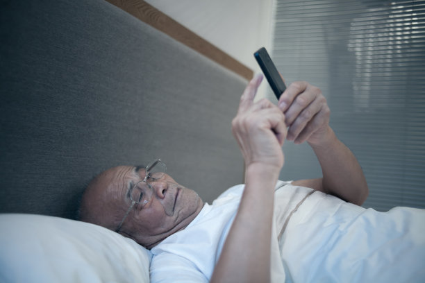 老年男人在卧室使用手机素材图片