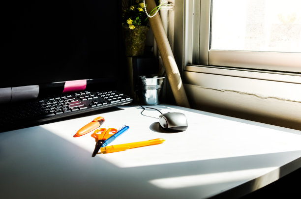 办公桌和电脑放在一张白色的桌子上，还有钢笔、剪刀和便笺本。图片下载