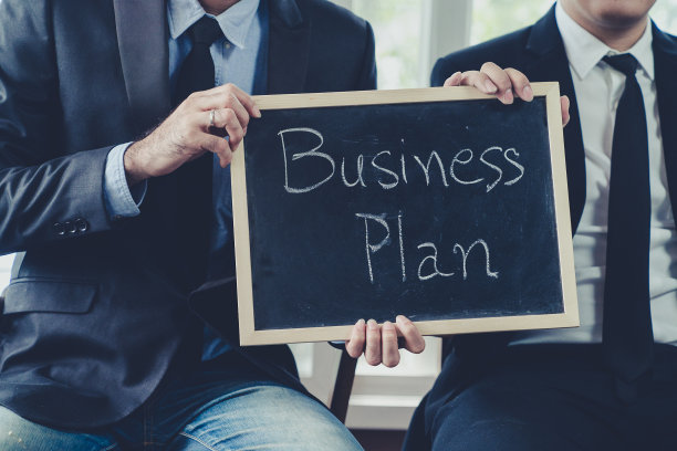 在粉笔黑板上写着“商业计划”的商人穿着黑色西装;经营理念照片。图片下载
