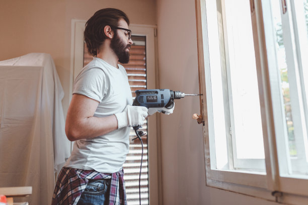 英俊的大胡子拿着电钻正在装修房子图片下载