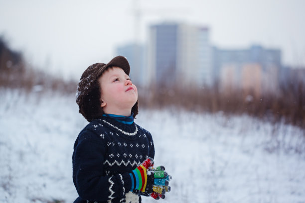 冬天小男孩的肖像穿着一件有鹿的针织毛衣，在户外下雪的时候。图片下载