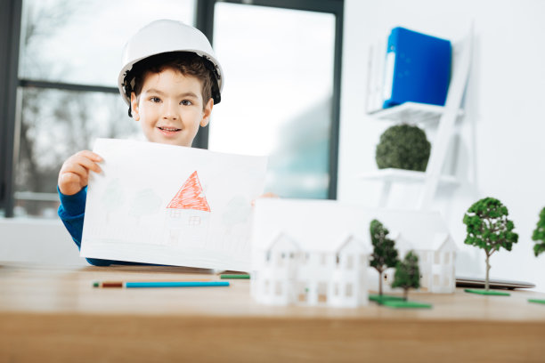 愉快的男孩戴着安全帽展示房子的图片图片下载