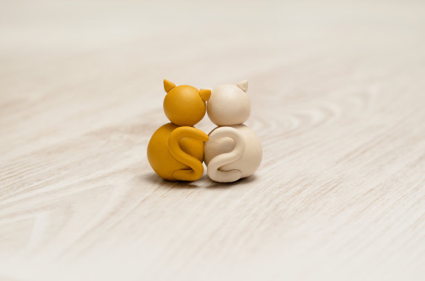 两个在恋爱中的极简主义动物形象。可爱的猫橡皮泥模型有心形尾巴。情人节快乐。图片下载