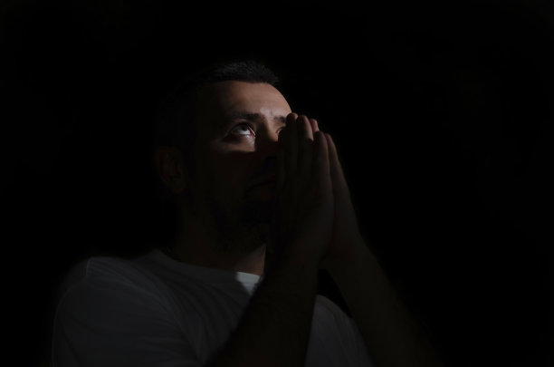 一个男人在黑暗的房间里向上帝祈祷图片下载