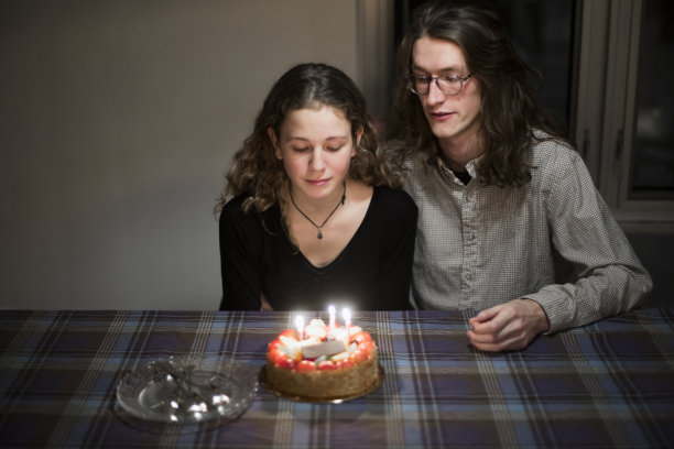 一个年轻女人和她的男朋友正要在她的生日蛋糕上吹蜡烛图片下载