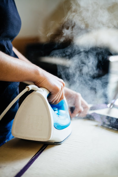 年轻时装设计师熨烫纺织品图片下载