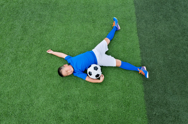 小男孩躺在足球场上素材图片