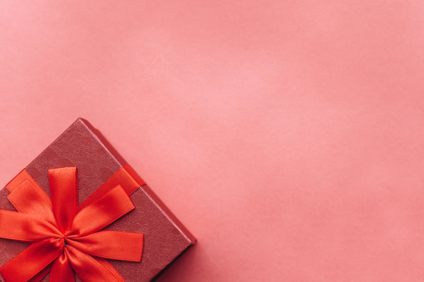 红色的漂亮的盒子与丝带和蝴蝶结在红色的背景。图片下载