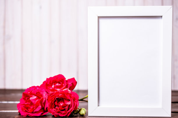 空白相框与copyspace和粉红色玫瑰花在木制背景。贺卡。图片下载