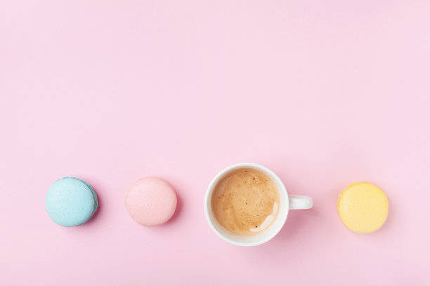 舒适的早晨早餐。一杯咖啡和彩色马卡龙在淡粉色的背景俯视图。时尚平铺风格。图片下载