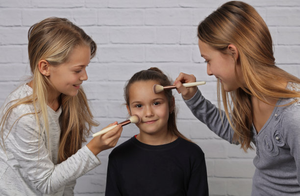 画像的三个可爱的微笑姐姐女孩有乐趣和玩化妆化妆品在家。幸福的家庭，团聚的概念图片下载