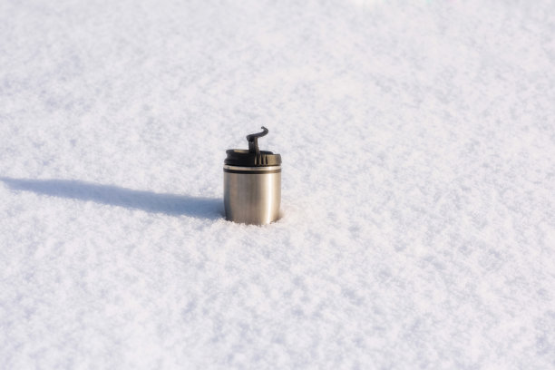 近距离图片热水瓶与热咖啡在冬天的雪。概念图片下载