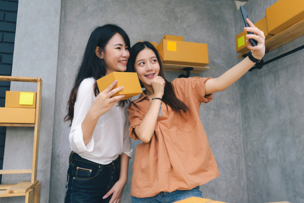 团队工作的亚洲女性自由职业者和博客评论产品工作的中小企业业务在家庭办公室与包裹递送在线客户通过交谈智能手机直播视频图片下载