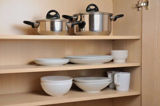 厨房碗柜里不同的白色盘子和平底锅。概念顺序在厨房的碗柜里。图片下载