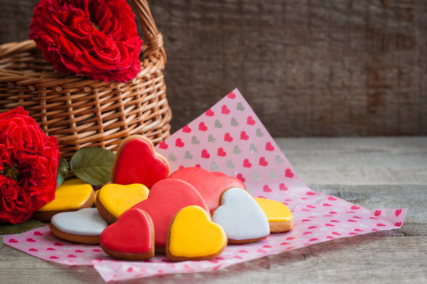 姜饼心型饼干，木质背景上点缀着玫瑰。情人节明信片的概念。图片下载