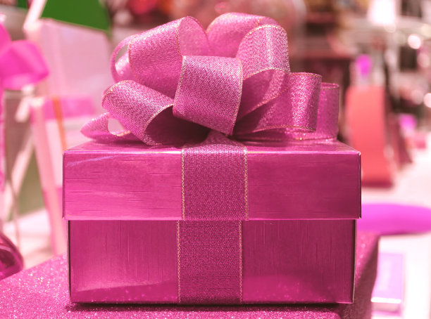闪亮的粉红色方形礼盒与Gritter粉红色丝带蝴蝶结，前视图与选择焦点和模糊的背景图片下载