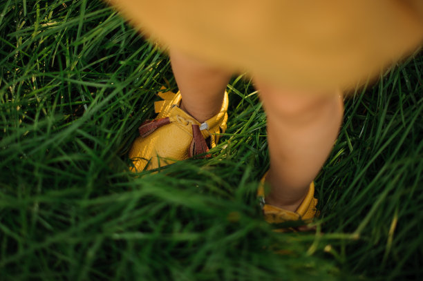 孩子的腿穿着黄色的鞋子在绿色的草地上图片下载