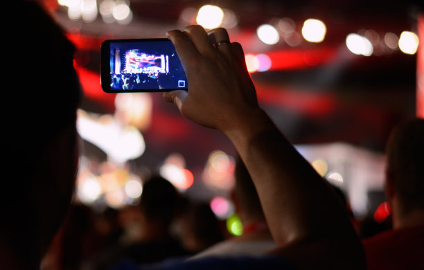 粉丝们拿着智能手机，在音乐会上享受图片下载