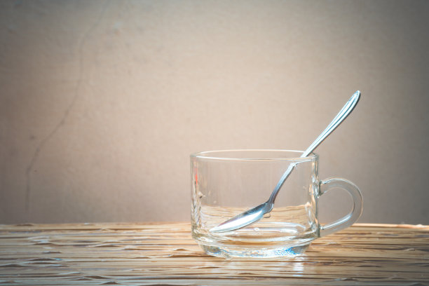 空咖啡杯和勺子放在木桌上。图片下载